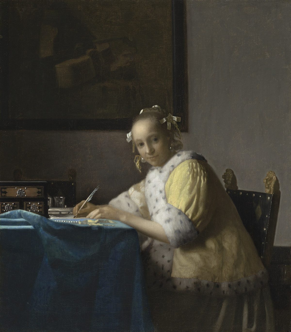 Vermeer, Donna che scrive una lettera: una giovane in giacca gialla scrive a un tavolo coperto da un panno blu e alza lo sguardo